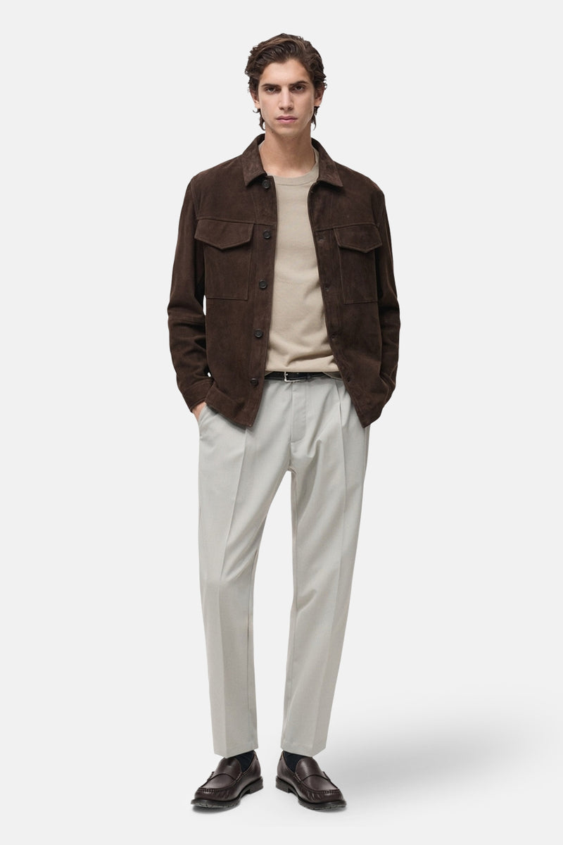 T-shirt beige à manches courtes de MANGO, porté avec une veste en daim marron et un pantalon clair.