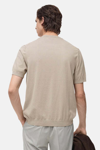 T-shirt beige à manches courtes par MANGO, avec ourlet côtelé et porté avec un pantalon gris.
