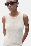 Top écru sans manches de MANGO, avec une bordure texturée et porté avec des lunettes de soleil noires et un bracelet doré.
