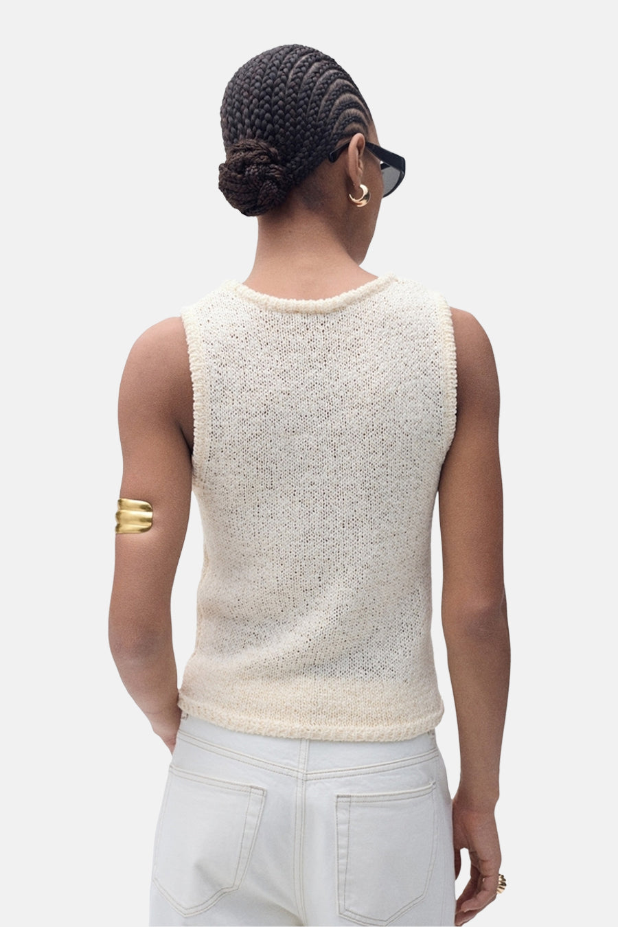 Top écru sans manches de MANGO, porté avec un jean blanc, une manchette dorée et des boucles d'oreilles dorées.