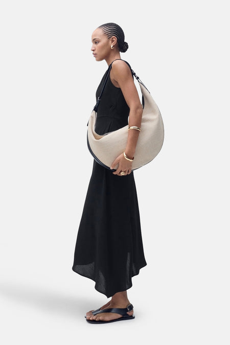 Zwarte jurk van MANGO, gedragen met een grote handtas en zwarte sandalen.