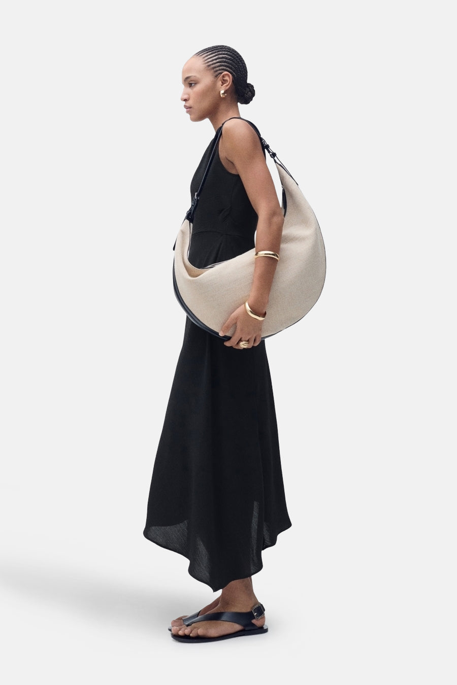 Robe noire de MANGO, portée avec un grand sac à main et des sandales noires.