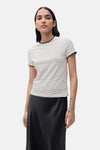 T-shirt à manches courtes beige de MANGO, rayures noires horizontales et finitions noires, porté avec une jupe noire.
