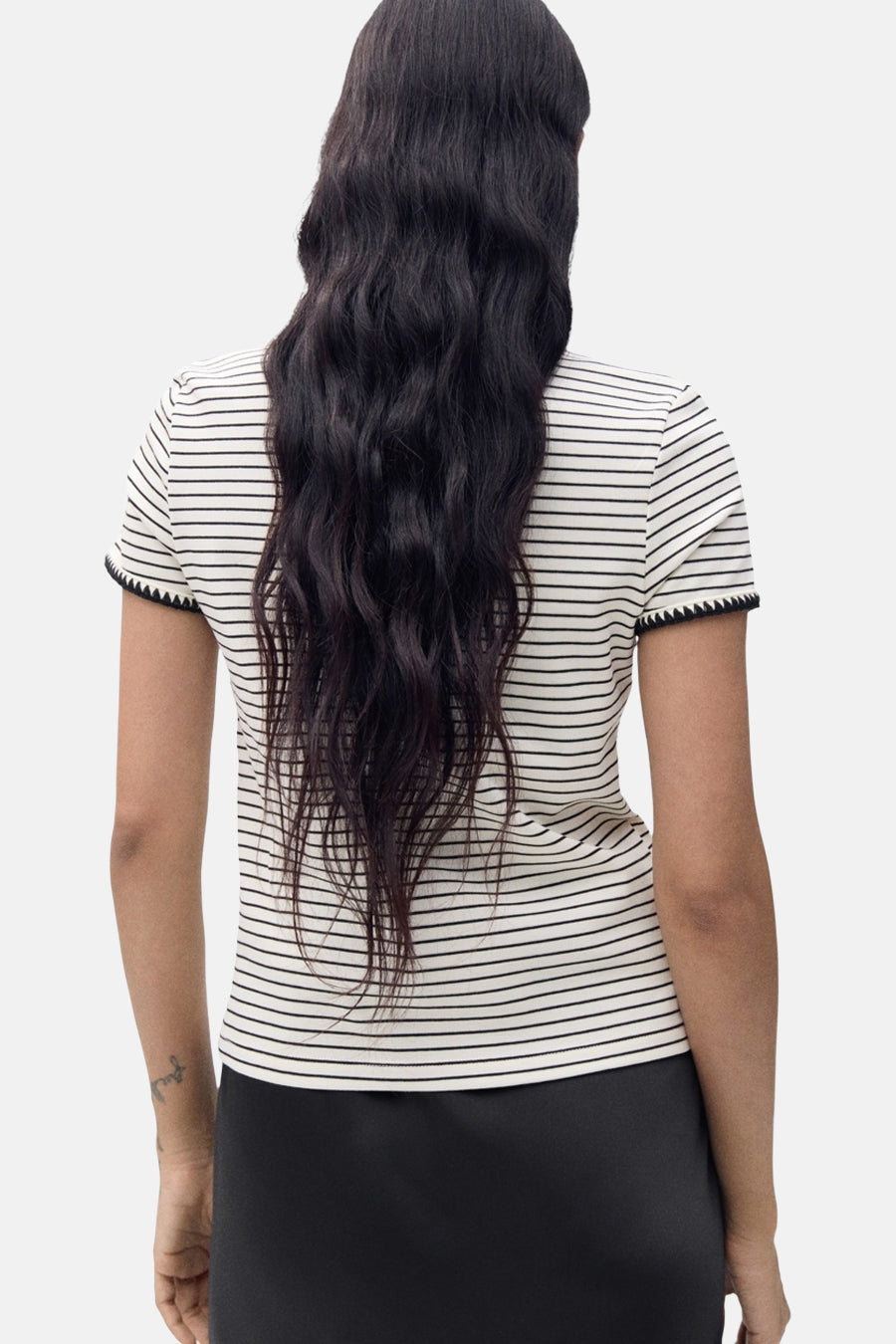 T-shirt beige à rayures by MANGO, manches courtes avec ourlet dentelé, porté avec une jupe noire.