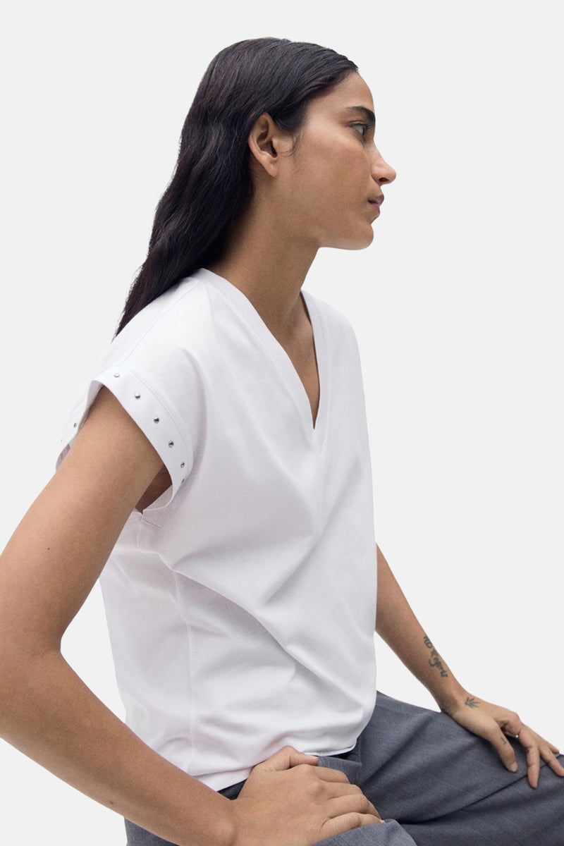 T-shirt blanc à manches courtes de MANGO, avec des détails cloutés aux épaules et une coupe décontractée.