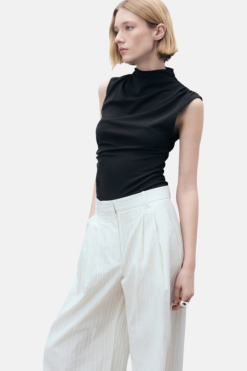 Top noir sans manches de MANGO, porté avec un pantalon rayé taille haute.