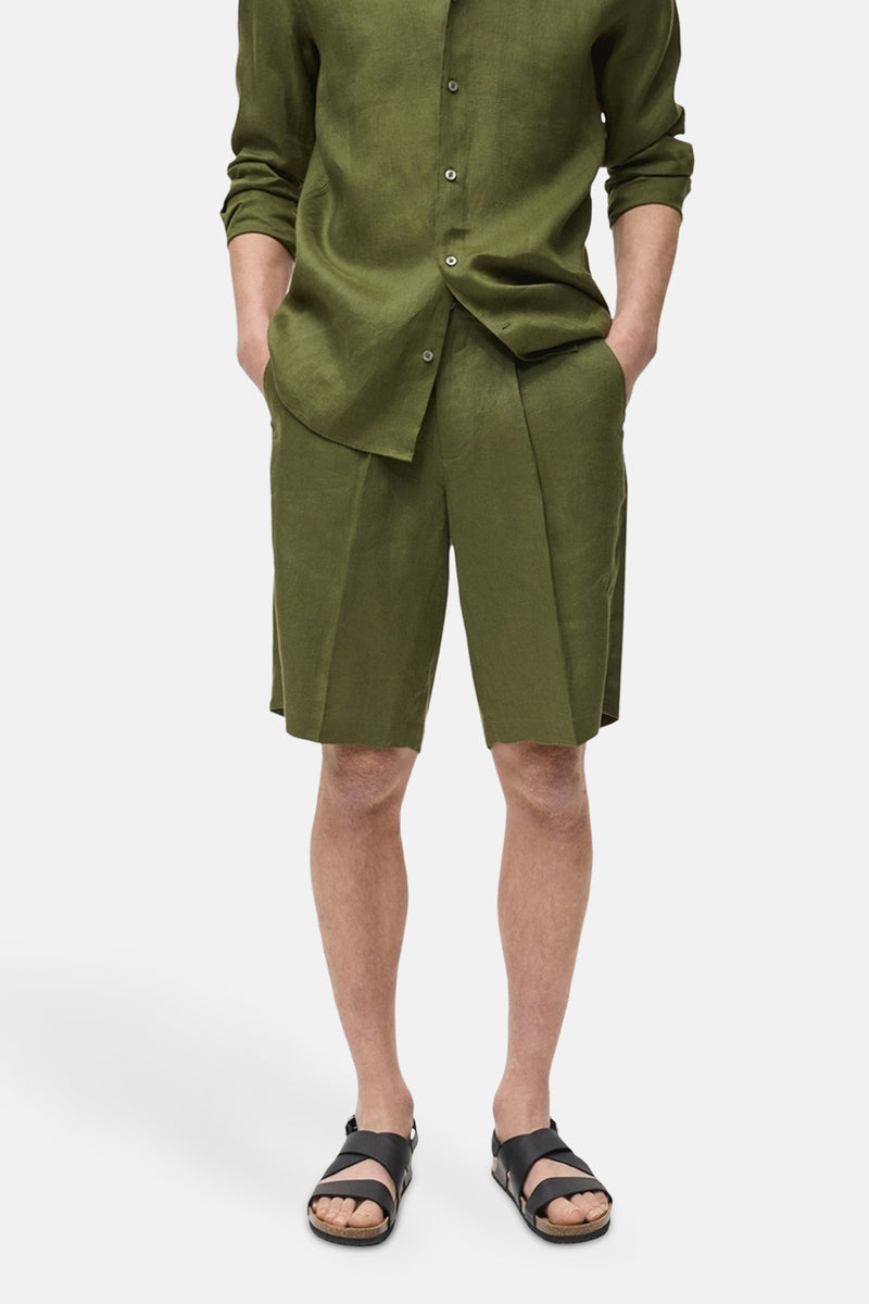Short vert de MANGO, porté avec une chemise verte assortie et des sandales en cuir noir.
