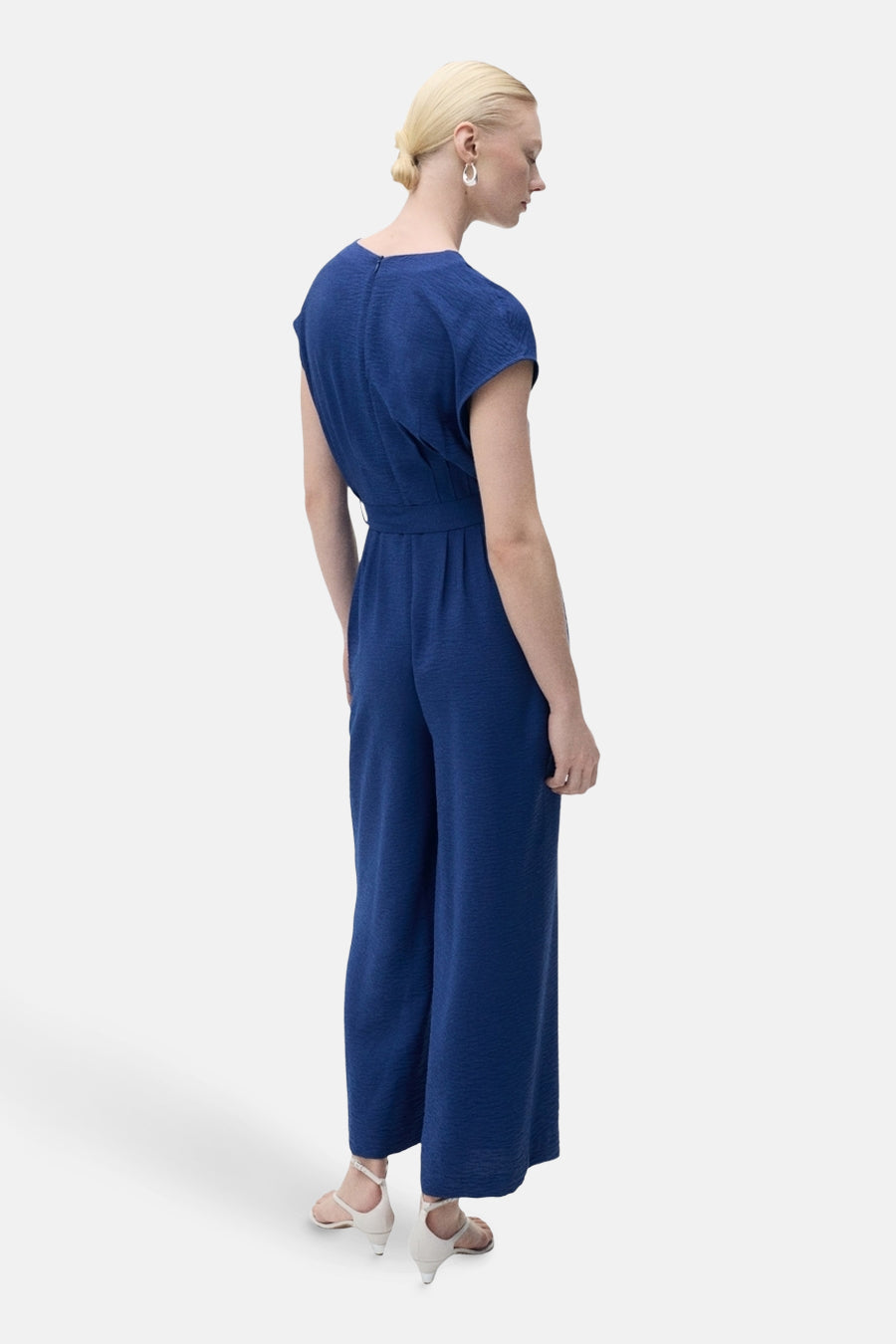 Marineblauwe jumpsuit van MANGO, met bijpassende riem en onopvallende ritssluiting aan de achterkant.