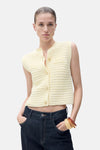 Gilet jaune en tricot de MANGO, boutonné et porté avec un jean taille basse.

