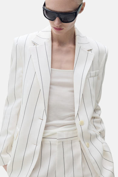 Witte blazer met strepen van MANGO, achtergezicht, gedragen met een zwarte zonnebril.