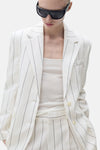 Witte blazer met strepen van MANGO, achtergezicht, gedragen met een zwarte zonnebril.