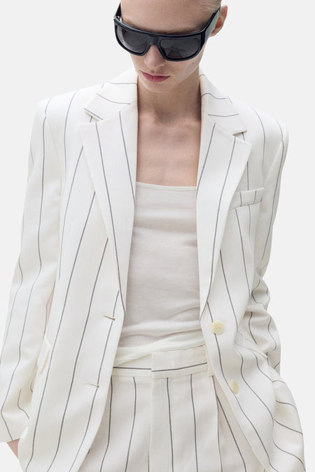 Witte blazer met strepen van MANGO, achtergezicht, gedragen met een zwarte zonnebril.