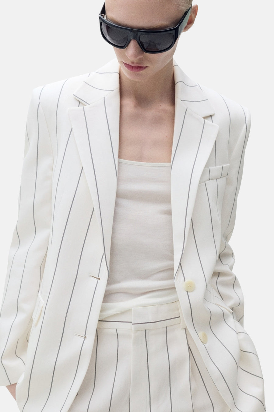 Witte blazer met strepen van MANGO, achtergezicht, gedragen met een zwarte zonnebril.