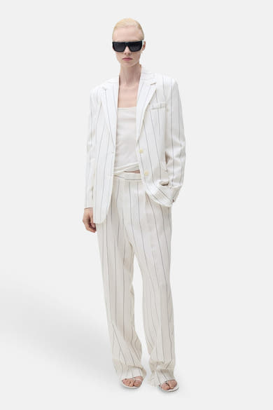 Witte gestreepte blazer van MANGO gedragen over een witte tanktop en een bijpassende gestreepte broek, met een zwarte zonnebril.