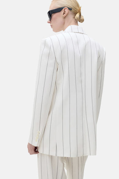 Blazer blanc à rayures par MANGO, vue arrière, porté avec des lunettes de soleil noires.