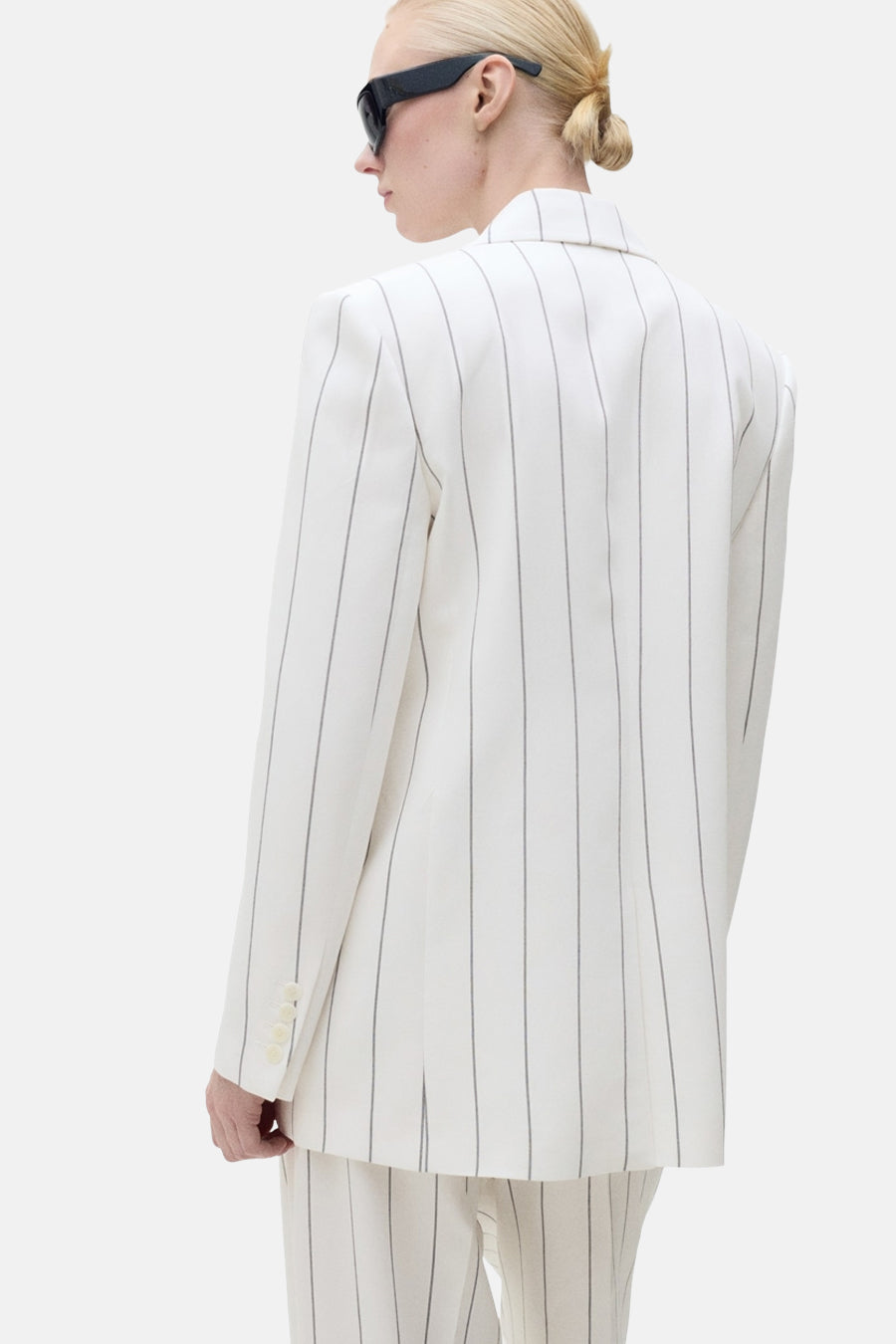Blazer blanc à rayures par MANGO, vue arrière, porté avec des lunettes de soleil noires.