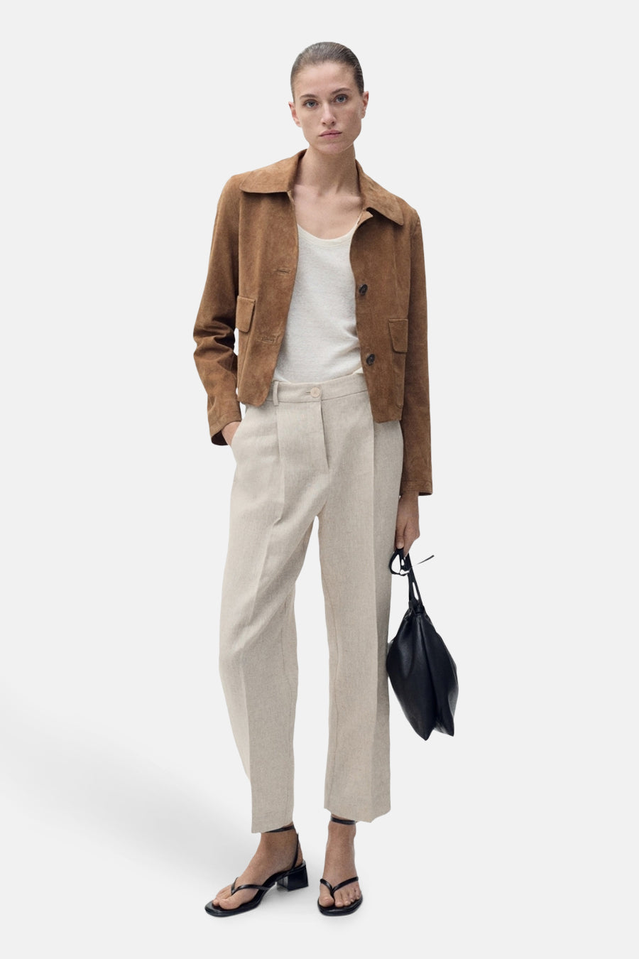 Beige broek van MANGO, gedragen met een gebroken witte top en een kort bruin leren jasje.