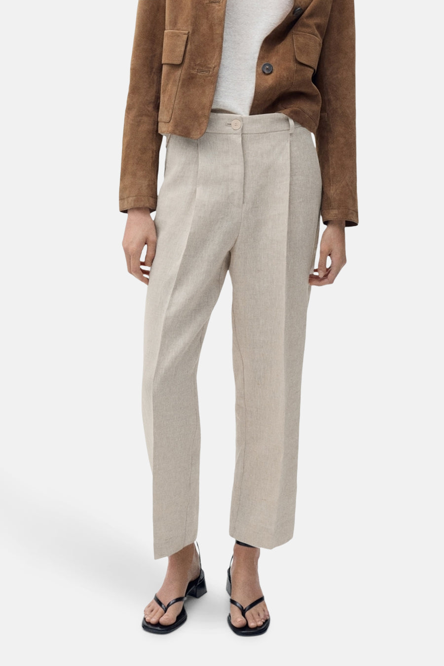 Beige linnen broek van MANGO, met een korte bruine jas en zwarte sandalen.