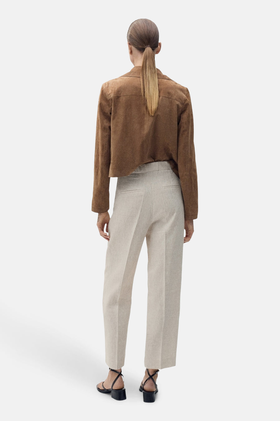 Beige broek van MANGO, rechte pasvorm, van linnenmix, gedragen met zwarte sandalen met hak.