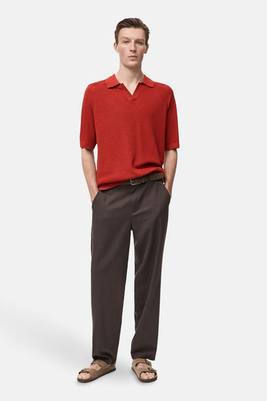 Rood poloshirt met korte mouwen van MANGO, gedragen met een bruine broek en beige sandalen.