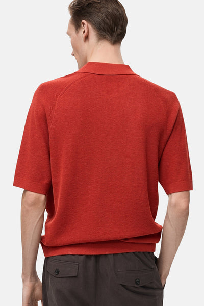 Polo à manches courtes rouge de MANGO, en maille texturée, porté avec un pantalon marron.