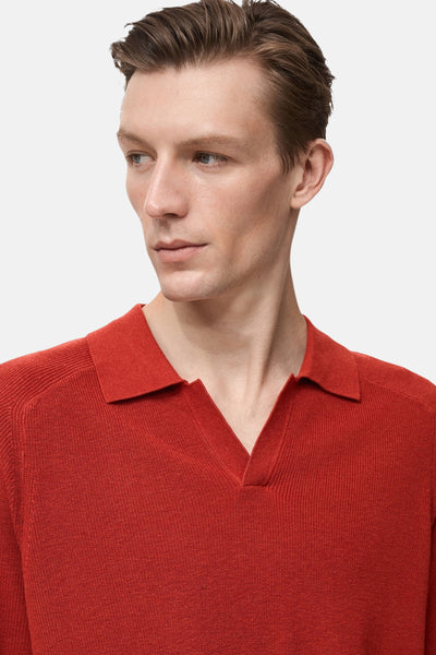 Polo à manches courtes rouge by MANGO, en maille fine, porté par un homme regardant sur le côté.

