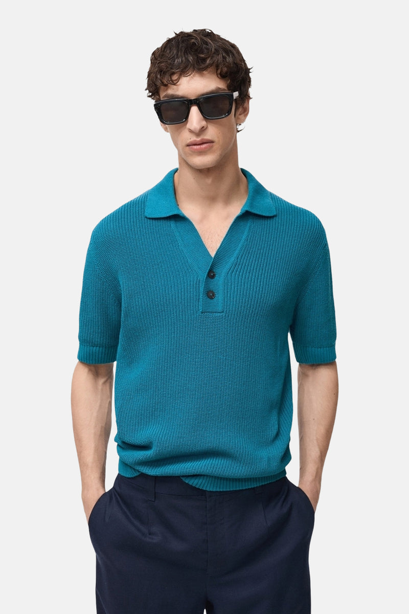 Turquoise poloshirt met korte mouwen van MANGO, ribgebreide textuur, gedragen met een marineblauwe broek.