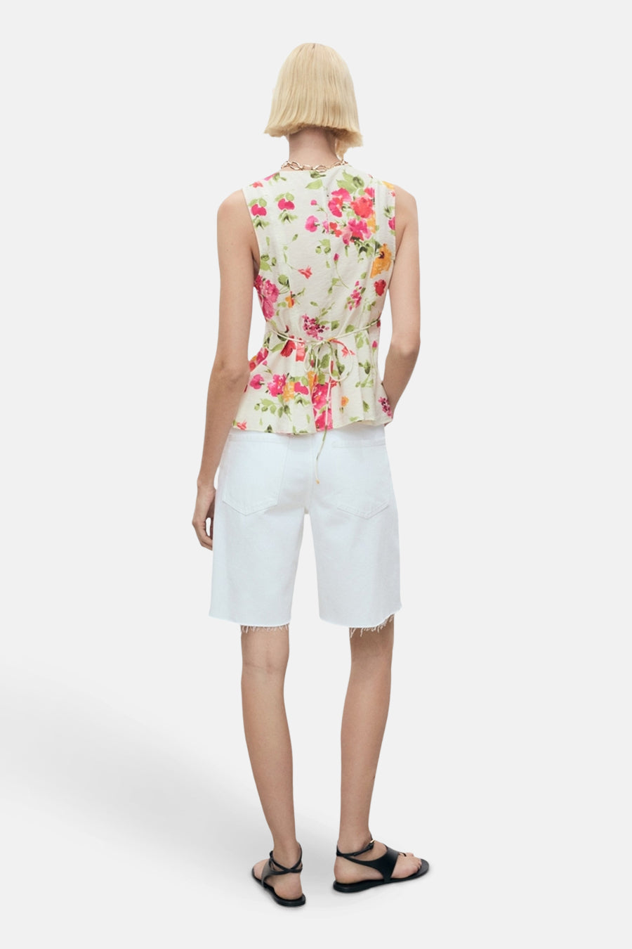 Blouse sans manches multicolore de MANGO, à motif floral, avec un cordon à nouer dans le dos et portée avec un short blanc.