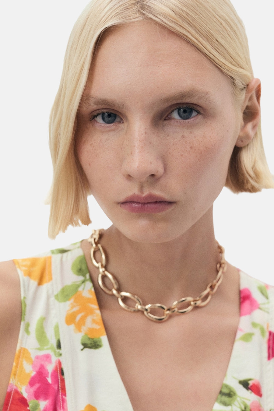 Blouse sans manches multicolore de MANGO, à imprimé floral lumineux avec un collier doré visible.
