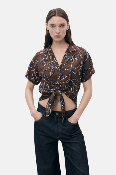 Multikleurig overhemd met korte mouwen van MANGO, met een bladmotief en een strik in de taille, gedragen met een donkerblauwe jeans.