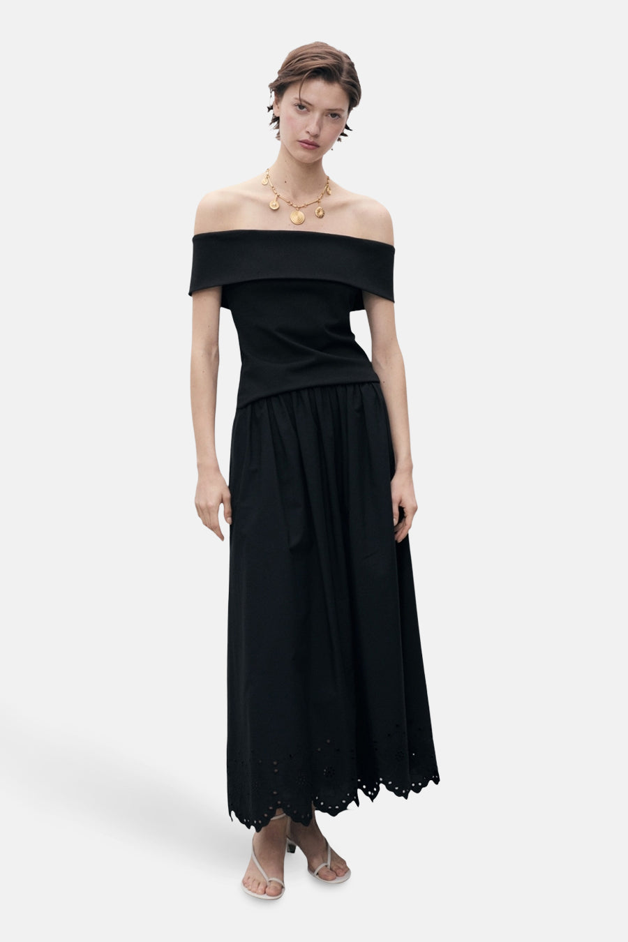 Zwarte lange rok van MANGO, met broderiedetail aan de zoom, gedragen met een zwarte top en een gouden ketting.