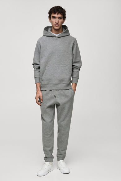 Grijze hoodie van MANGO, gedragen met een bijpassende joggingbroek en witte sneakers.