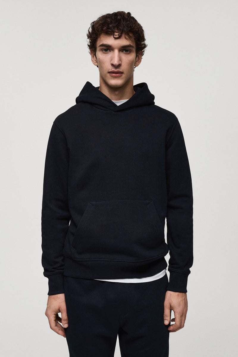 Marineblauwe hoodie van MANGO, met kangoeroezak en geribbelde zoom, gedragen met een wit T-shirt.