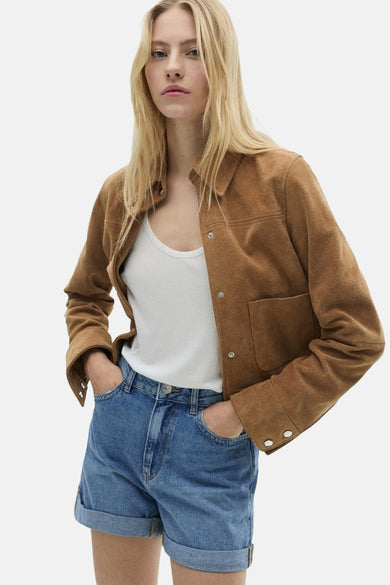Short bleu denim moyen by MANGO, porté avec une veste marron et un t-shirt blanc.