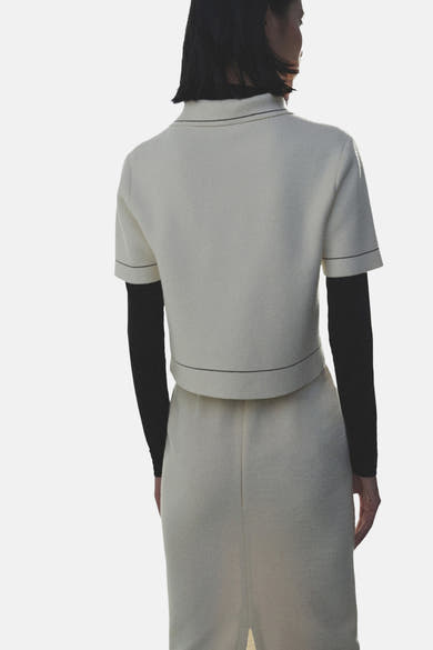 Gilet écru de MANGO, avec manches courtes et surpiqûres contrastantes, porté sur un haut noir à manches longues.