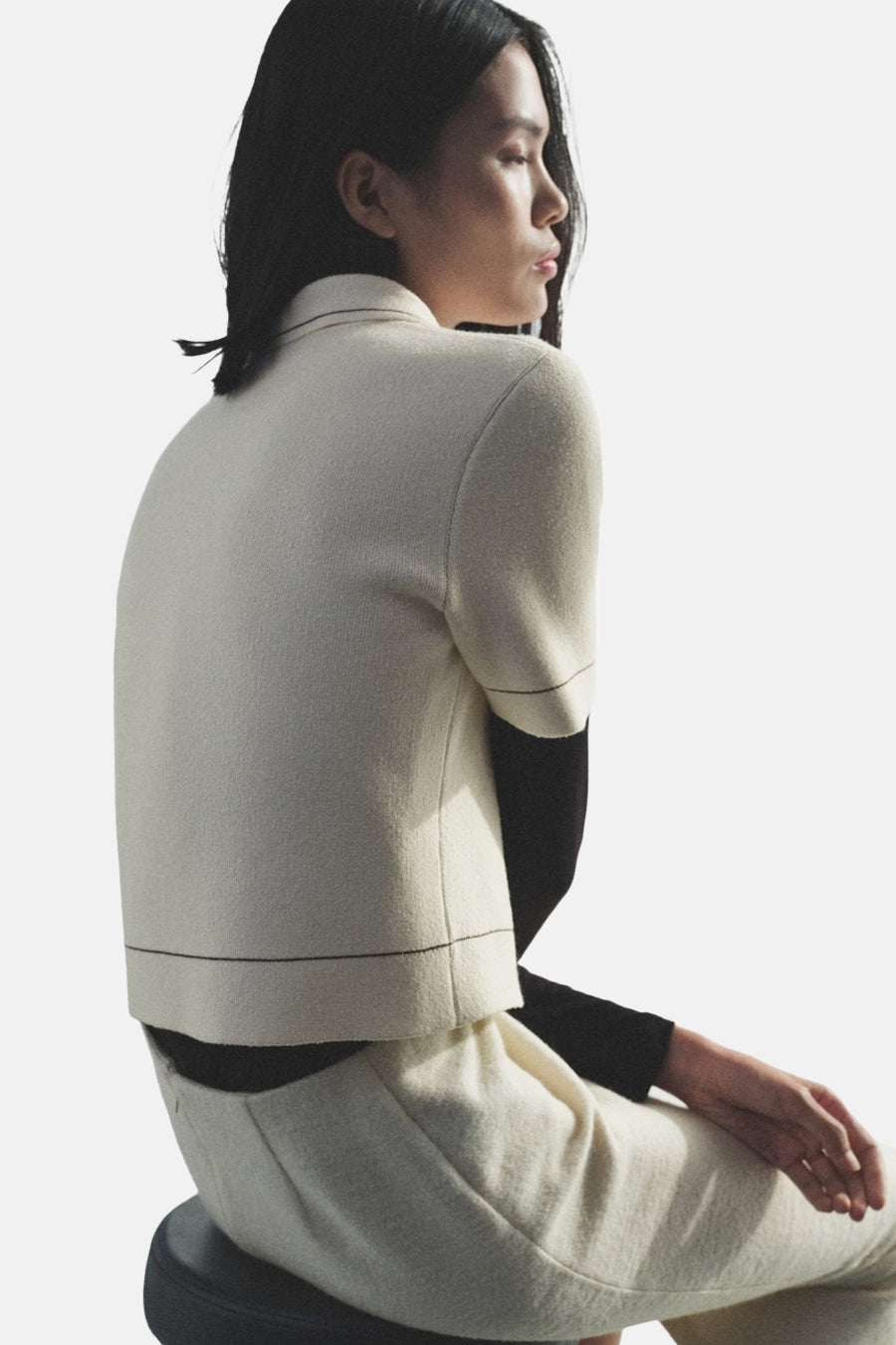 Ecru gilet van MANGO, gedragen met een zwarte trui met lange mouwen en een bijpassende broek.