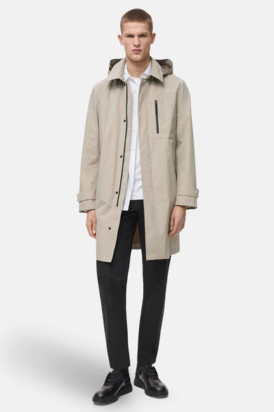 Manteau beige de MANGO, avec capuche, porté sur une chemise blanche et un pantalon noir.
