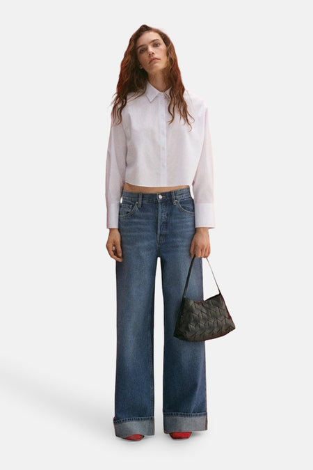Wit overhemd met lange mouwen van MANGO, gedragen met een wijde blauwe jeans en een zwarte tas.