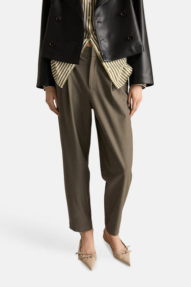 Kaki broek van MANGO, met een wijde pasvorm en platte sandalen met bandjes.