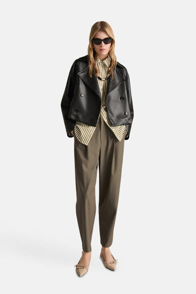 Kaki broek van MANGO, pantalonstijl met een groen gestreept overhemd en een zwart leren jasje.