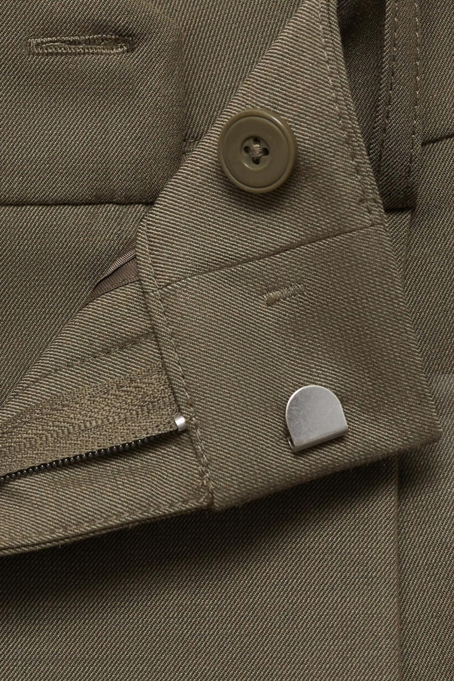 Kaki broek van MANGO, met ritssluiting en olijfkleurige knoop, close-up.