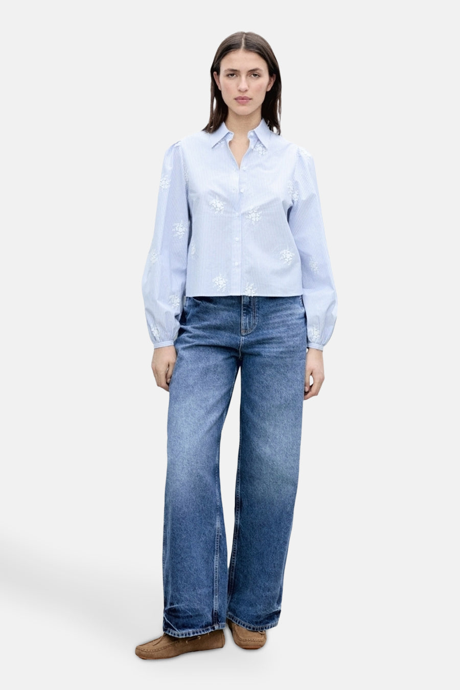 Chemise bleu à rayures, à manches longues de MANGO, ornée de motifs floraux brodés. Portée avec un jean large et des mocassins marron.