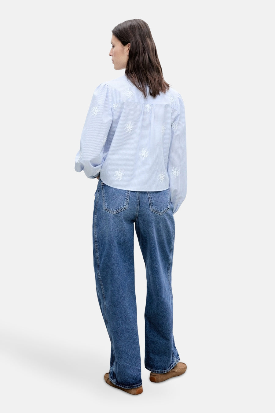Chemisier à manches longues bleu à rayures de MANGO, orné de broderies florales blanches, porté avec un jean ample.
