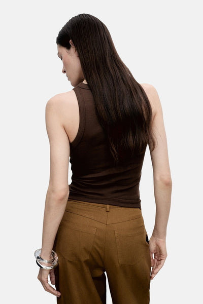 Bruine geribde tanktop van MANGO, gedragen met een bruine broek met hoge taille en een transparante armband.