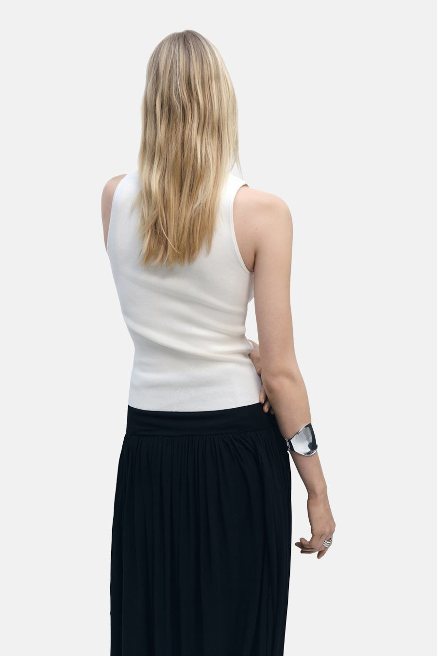 Top sans manches écru de MANGO, porté avec une longue jupe noire fluide et un bracelet argenté.
