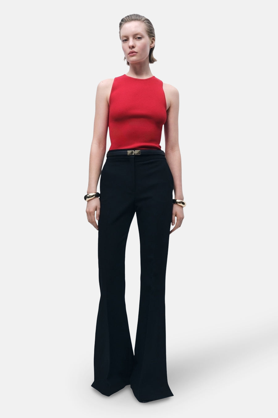 Rood mouwloos topje van MANGO, gedragen met een zwarte wijde broek en gouden armbanden.
