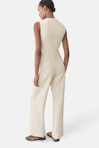 Ecru jumpsuit van MANGO, slim fit, wijde broek, getextureerde stof en bruine platte schoenen.