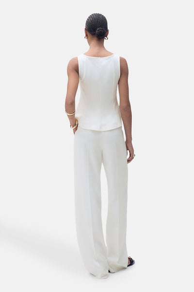 Top sans manches blanc de MANGO, porté avec un pantalon blanc ample, vue de dos.
