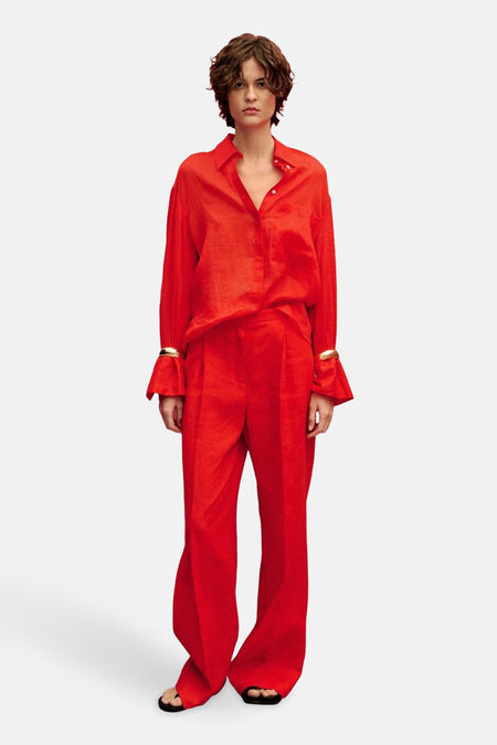 Rood overhemd met lange mouwen van MANGO, gedragen met een bijpassende rode broek en gouden armbanden.