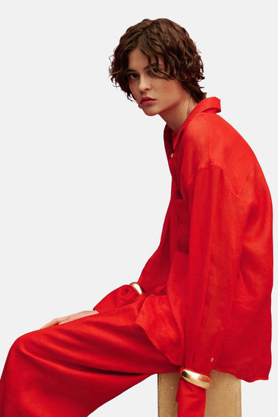 Rood overhemd met lange mouwen van MANGO, gedragen met een rode broek en gouden armbanden.